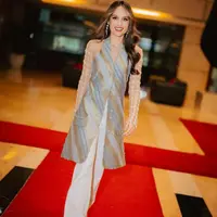 Ia juga mengenakan atasan panjang halter neck model batik dipadukan gloves panjang lace serta celana panjang warna putih. [@claurakiehl]