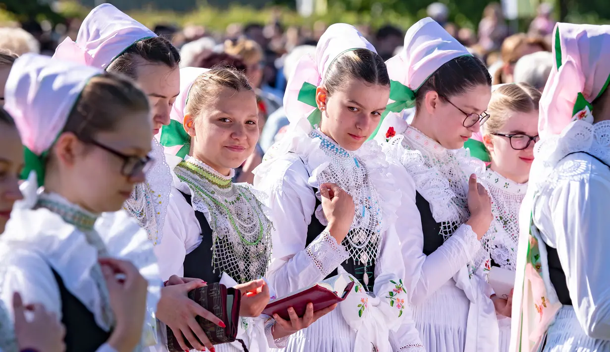 Sejumlah remaja wanita mengenakan pakaian tradisional Sorbs berdoa saat mengikuti prosesi Whit Monday di gereja di Rosenthal, Jerman (21/5). Prosesi tradisional ini di gelar di dekat perbatasan Jerman-Polandia. (AP Photo / Jens Meyer)