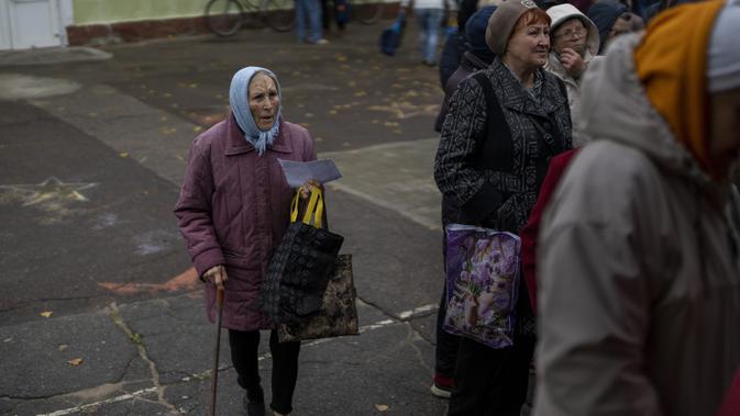Orang-orang mengantre untuk menerima jatah roti setiap hari di sebuah sekolah di Mykolaiv, Ukraina, Selasa (25/10/2022). Penduduk Mykolaiv mengambil roti dari satu-satunya titik distribusi makanan di Varvarivka. (AP Photo/Emilio Morenatti)