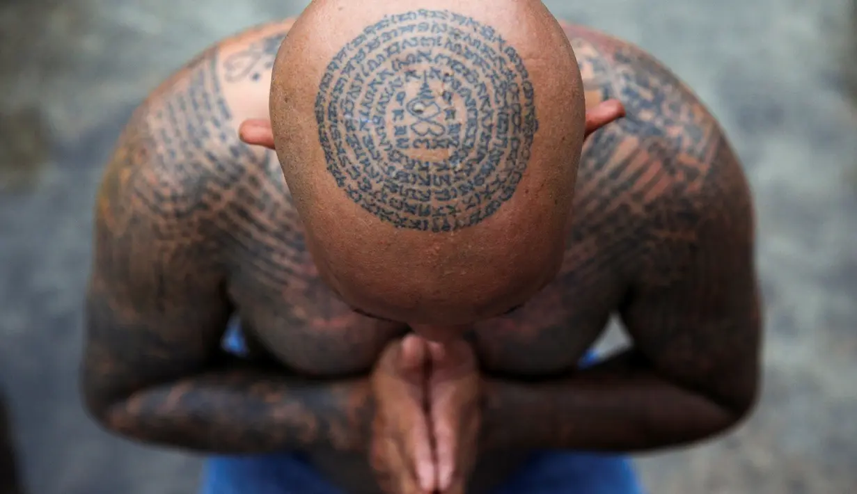 Seorang pria bertato berdoa saat mengikuti Festival Tato Suci di kuil Wat Bang Phra, Nakhon Pathom, Thailand (16/3). Di festival ini, peserta mengalami kesurupan dengan gaya sesuai gambar tato yang mereka miliki. (Reuters/Athit Perawongmetha)