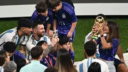 Pemain Argentina, Lionel Messi memotret istrinya, Antonela Ruccuzzo (kanan) yang sedang memegang trofi Piala Dunia 2022 setelah timnya berhasil mengalahkan Prancis pada laga final yang berlangsung di Lusail Stadium, Qatar, Minggu (18/12/2022). Albiceleste menang 4-2 atas Prancis di babak penalti. (AFP/Jewel Samad)
