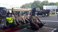 Saat para polisi salat berjemaah, dua rekan mereka menjaga di tepi jalan tol. (Liputan6.com/Panji Prayitno)