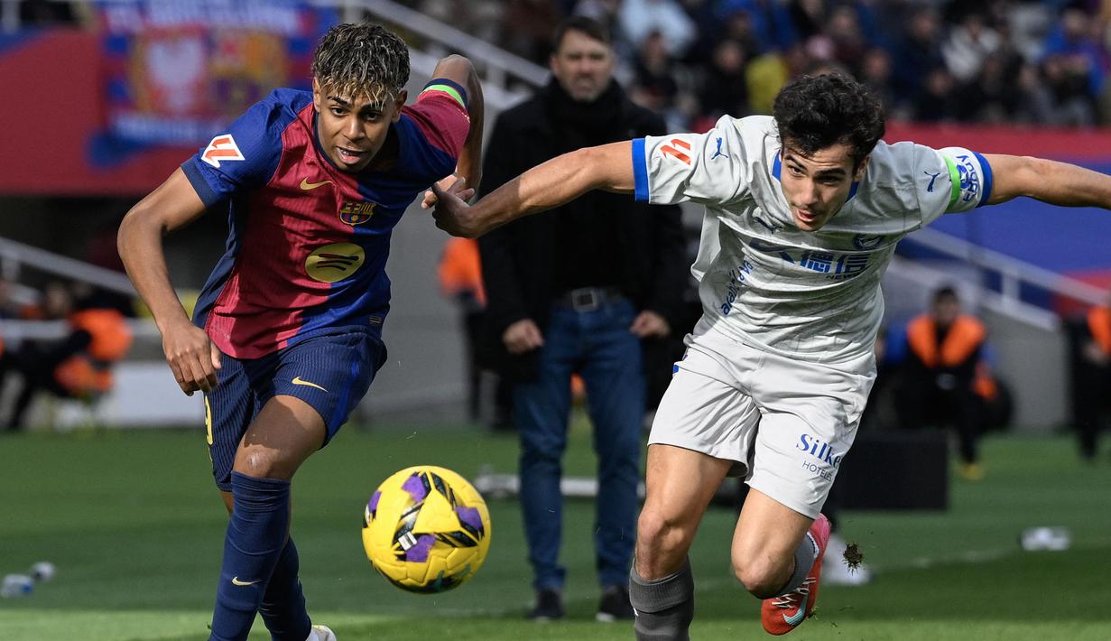 Pemain Barcelona, Lamine Yamal (kiri) berebut bola dengan pemain Deportivo Alaves, Manuel Sanchez dalam laga lanjutan Liga Spanyol 2024/2025 di Estadi Olimpic Lluis Companys, Barcelona, Spanyol, Minggu (02/02/2025) waktu setempat. (AFP/Josep Lago)