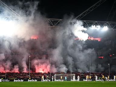 Suporter Genoa menyalakan suar saat pertandingan melawan Inter Milan pada laga lanjutan Liga Italia 2023/2024 di Stadion Luigi Ferraris, Genoa, Italia, Sabtu (30/12/2023) dini hari WIB. (AFP/Piero Cruciatti)