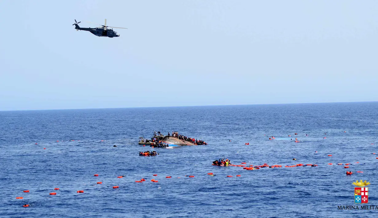 Helikopter berusaha mendekati sebuah perahu yang berisi para migran setelah terbalik di lepas pantai Libya, Rabu (25/5). Tujuh orang tewas tenggelam, sementara 500 orang lainnya berhasil diselamatkan dalam insiden tersebut. (STR/AFP MARINA MILITARE/AFP)