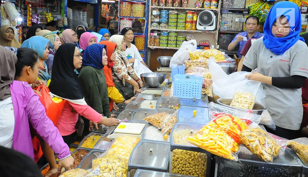 Pedagang kue kering melayani pembeli di Pasar Jatinegara, Jakarta, Senin (27/5/2019). Jelang Idul Fitri 2019, banyak warga berburu makanan ringan seperti kue kering untuk jamuan di hari raya. (Liputan6.com/Angga Yuniar)