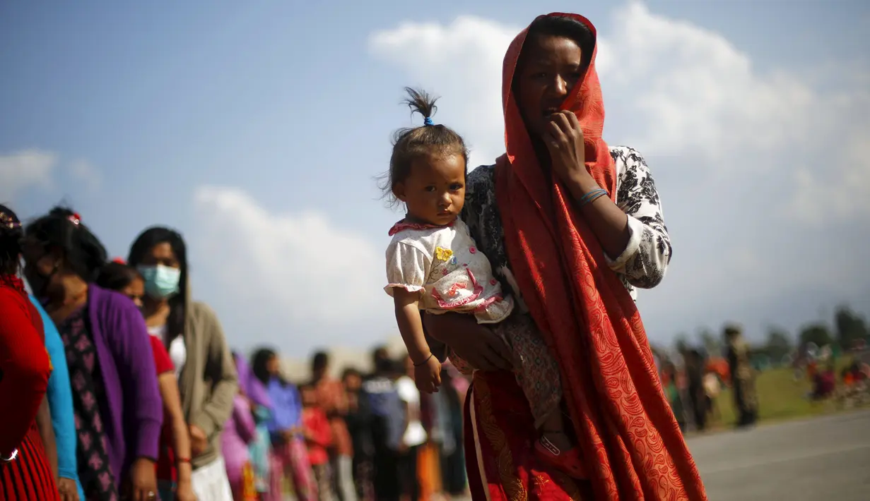 Seorang korban gempa menggendong anaknya mengantre untuk  mendapatkan makanan dan minuman di lokasi pengungsian, di Kathmandu, Nepal, Senin (4/5/2015). Gempa berkekuatan 7,8 yang meluluhlantakkan Nepal pada 25 April 2015 lalu. (REUTERS/Adnan Abidi)