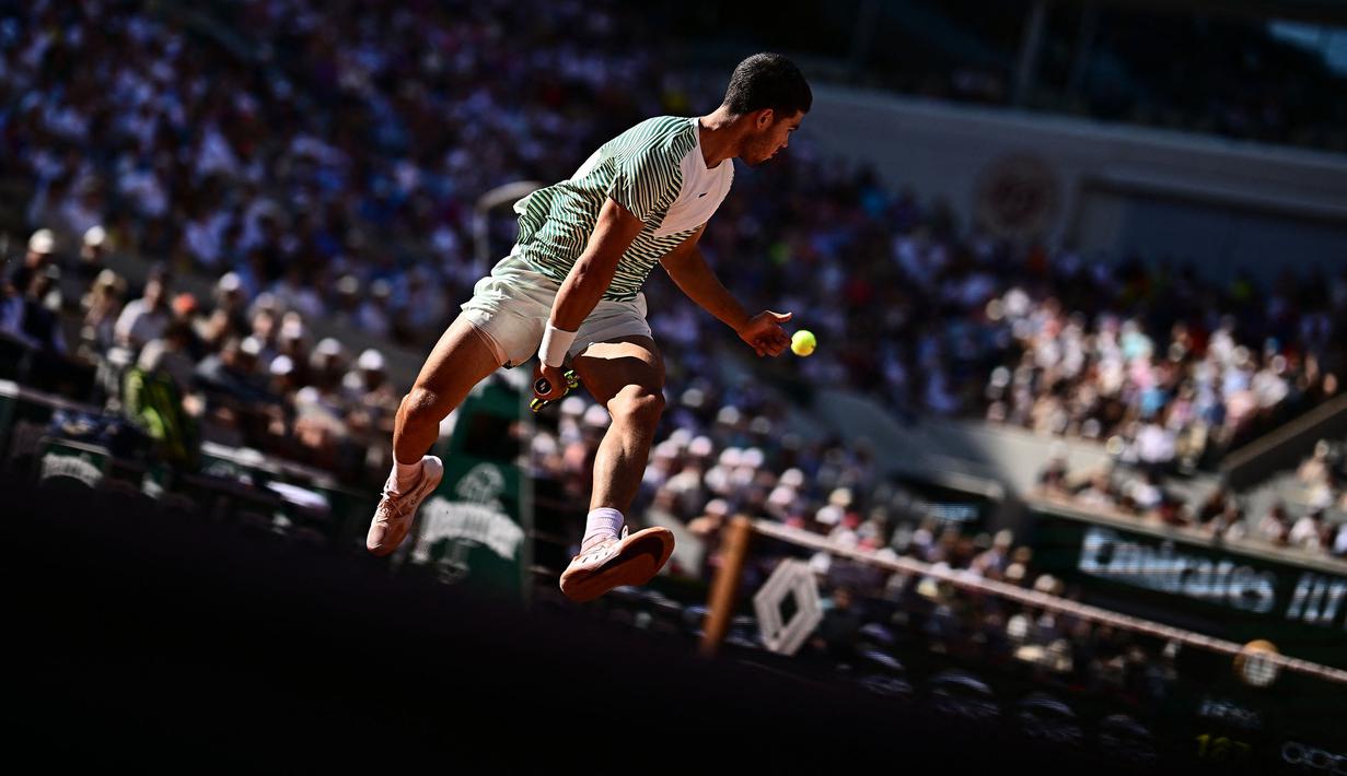 Petenis Spanyol, Carlos Alcaraz Garfia berusaha mengembalikan bola di antara kedua kakinya saat laga hari kedelapan Prancis Terbuka 2023 melawan petenis Italia, Lorenzo Musetti di Roland Garros, Paris, 4 Juni 2023. (AFP/Julien De Rosa)