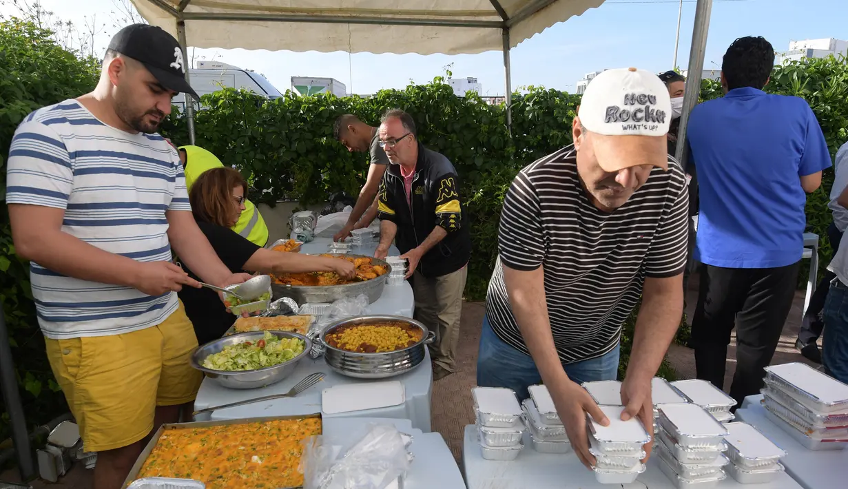 Relawan Tunisia membagikan makanan berbuka puasa gratis selama bulan suci Ramadan di Ariana dekat Tunis (7/5/2020). Masjid-masjid di Aljazair, Maroko dan Tunisia telah ditutup untuk membatasi penyebaran Covid-19, mencegah doa malam khusus. (AFP/Fethi Belad)
