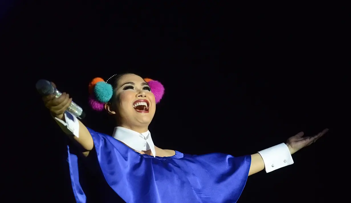 Dibalut gaun bewarna umgu menyala dan hiasan kepala bewarna-warni dengan aksen bulu-bulu, wanita asal Jakarta ini terlihat menikmati momen bernyanyi dalam acara Kahitna 30 Years Anniversary Love Festival pada tahun 2016 silam. (Kapanlagi/Bambang E Ros)