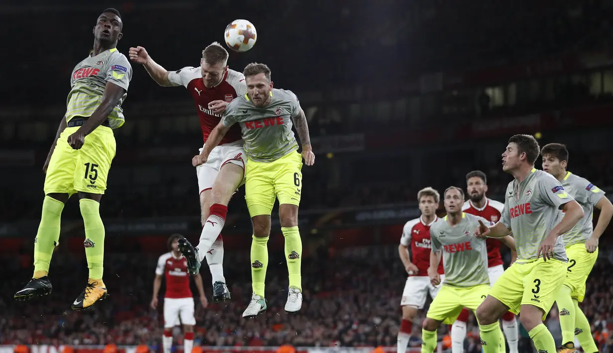 Bek Arsenal, Per Mertesacker, duel udara dengan striker FC Cologne, Jhon Andres Cordoba, pada laga Liga Europa di Stadion Emirates, London, Rabu (14/9/2017). Arsenal menang 3-1 atas Cologne. (AFP/Adrian Dennis)