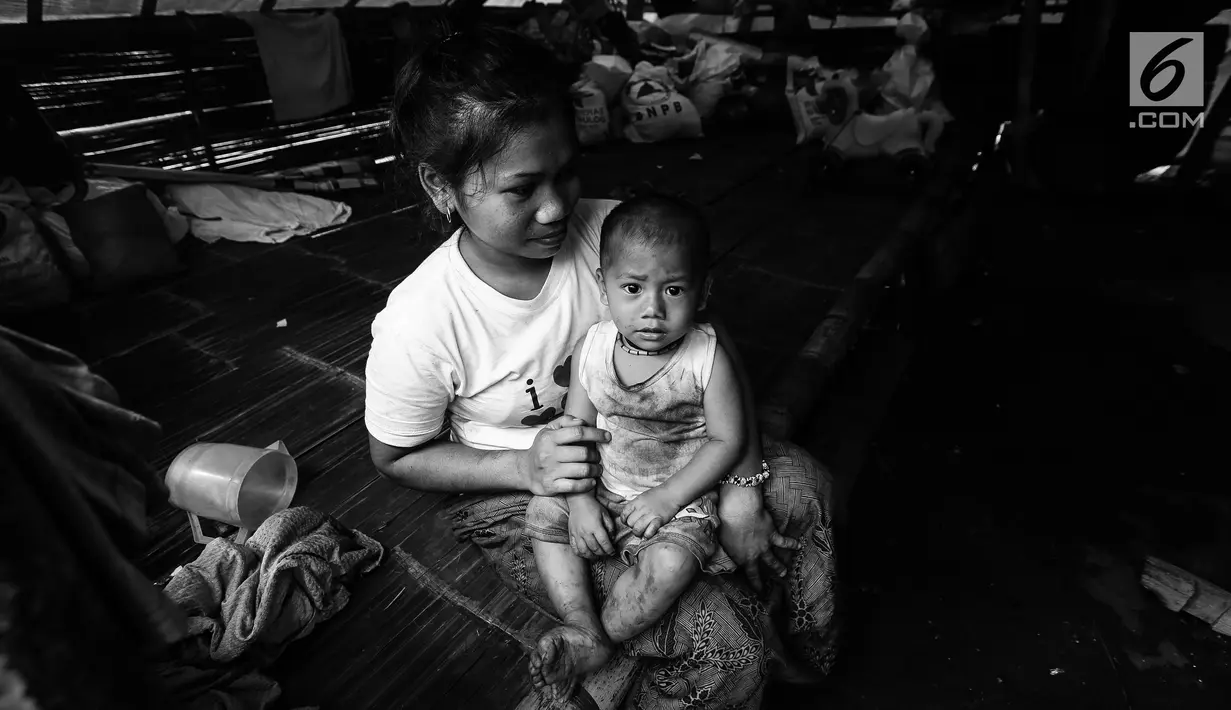 Seorang ibu Suku Baduy Luar sedang memangku anaknya di dalam rumah di lokasi bekas kebakaran Kampung Cisaban II, Desa Kanekes, Banten, Kamis (01/6). Kebakaran pada pekan lalu yang menghanguskan 83 rumah Suku Baduy Luar. (Liputan6.com/Fery Pradolo)