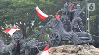 Massa aksi demo tolak omnibus law UU Cipta Kerja naik ke atas patung arjuna wiwaha mengibarkan bendera merah putih di Jalan Medan Merdeka Barat, Jakarta Pusat, Selasa (20/10/2020). (merdeka.com/ Arie Basuki)