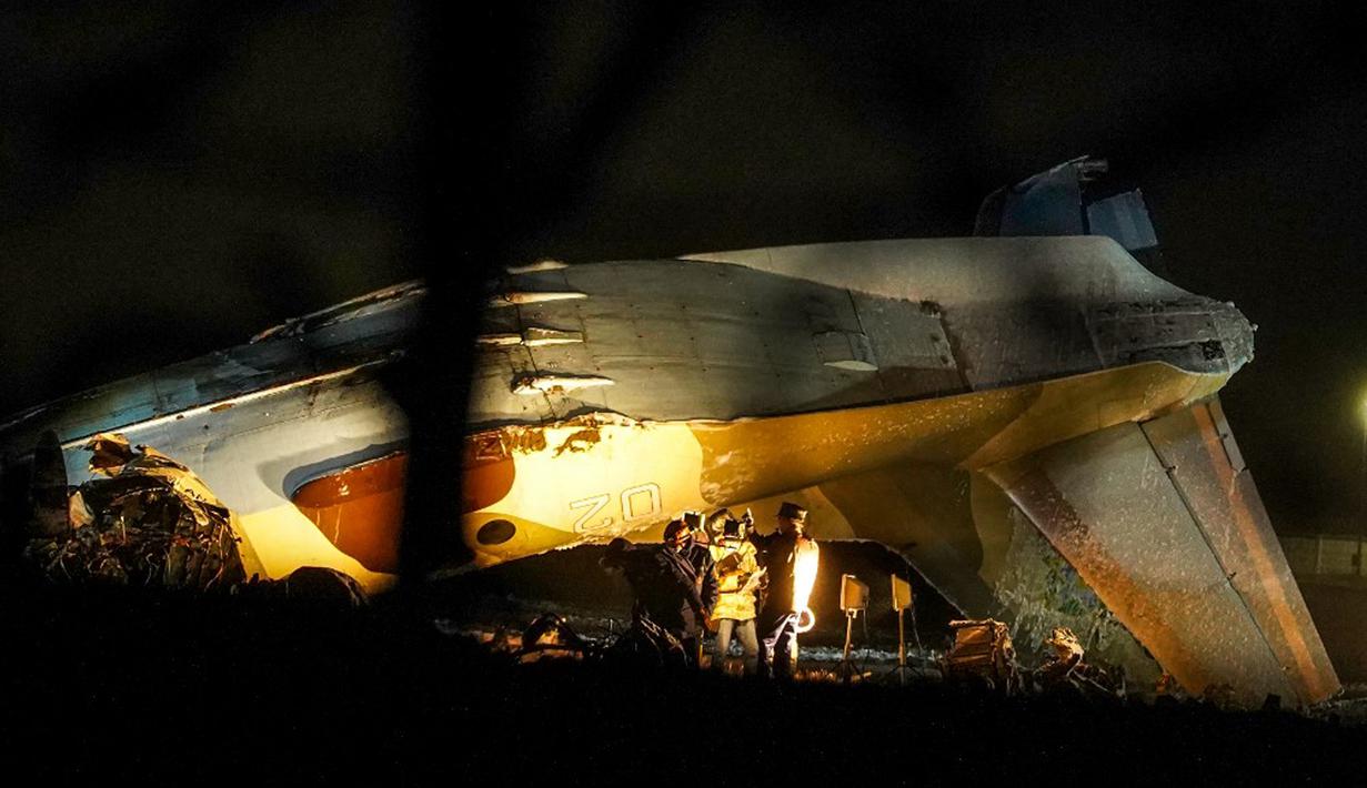 Penyelidik bekerja di lokasi jatuhnya pesawat Antonov An-26 di Bandara Almaty, Kazakhstan, Sabtu (13/3/2021). Kementerian Situasi Darurat Kazakhstan mengonfirmasi insiden tersebut menewaskan empat dari enam orang di dalamnya. (Abduaziz MADYAROV/AFP)
