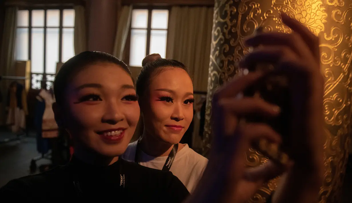 Dua model berselfie di belakang panggung sebelum memamerkan koleksi oleh Zhang Kejia selama China Fashion Week di Beijing (26/3). (AFP Photo/Nicolas Asfouri)