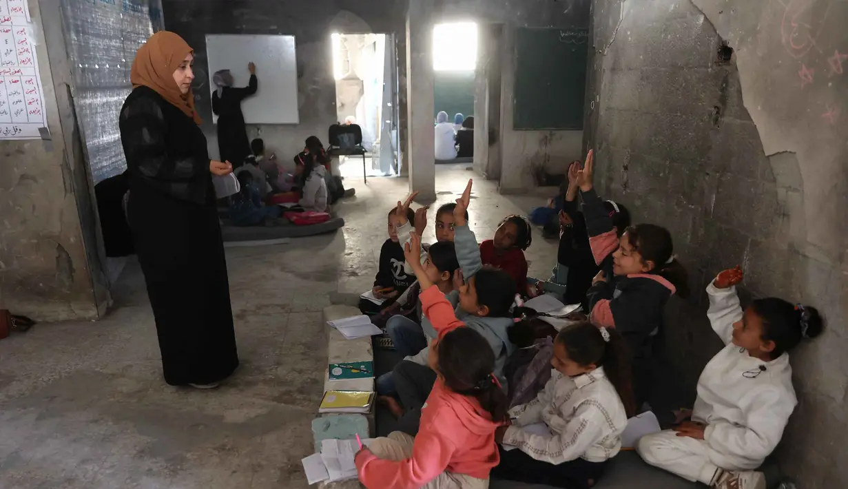 Di dalam tenda-tenda darurat, kamp pengungsi Jabalia, Jalur Gaza Utara, Sekolah Mada tetap beroperasi sebagai fasilitas pendidikan darurat di tengah konflik Israel dan Hamas yang masih berlangsung di Gaza. Tampak dalam foto, anak-anak pengungsi Palestina mengikuti belajar mengajar di dalam tenda di Sekolah Mada, kamp pengungsi Jabalia, Jalur Gaza Utara pada 13 April 2026. (Omar AL-QATTAA/AFP)