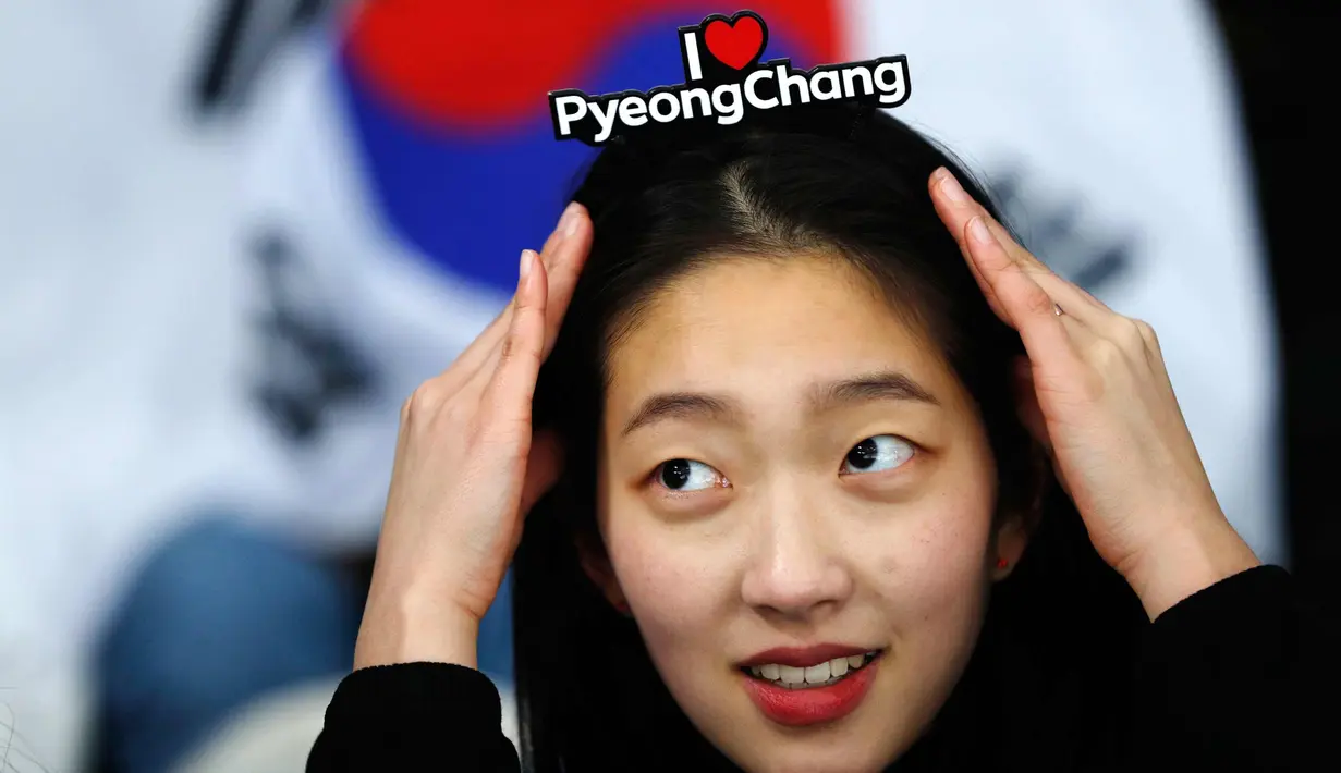 Penggemar wanita Korea Selatan menyesuaikan ikat kepalanya bertuliskan "I Love PyeongChang" saat menunggu pertandingan lomba skater 1.500 meter putra selama Olimpiade Musim Dingin 2018 di Gangneung Oval, Korea Selatan, (13/2). (AP Photo/John Locher)