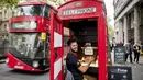 Seorang pria bernama Fouad Choaibi bekerja mereparasi ponsel didalam kotak telepon merah di Southhampton Row, London (20/10). Menjamurnya ponsel, membuat telepon umum di Inggris ini tidak beroperasi lagi. (AFP Photo/Tolga Akmen)