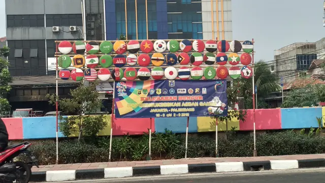 45 gambar bendera peserta Asian Games yang disajikan menggunakan tampah beras yang digantung pada tiang bambu di bantaran Kali Sentiong.  (Liputan6.com/Ika Defianti)
