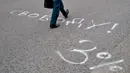 Seorang pria berjalan di halaman aspal yang dilukis dengan tulisan "Kebebasan! 3%", mengacu pada Alexander Lukashenko, yang dijuluki "Sasha 3 persen" dalam ejekan pada peringkat populernya yang seharusnya rendah, di Minsk (25/8/2020). (AFP/Sergei Gapon)