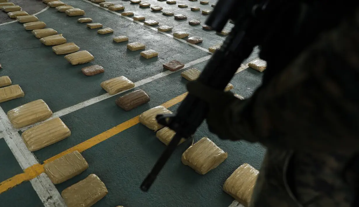 Polisi menjaga ratusan paket ganja sitaan saat konferensi pers di Markas Polisi Perbatasan Panama, Gamboa, Panama, Selasa (1/9/2020). Menurut pihak berwenang, sebanyak 758 paket ganja disita di Pantai Pasifik dekat perbatasan Kolombia. (AP Photo/Arnulfo Franco)