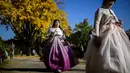 Para wanita mengenakan pakaian tradisional Hanbok berjalan di depan pohon gingko dengan dedaunan musim gugur saat mereka mengunjungi halaman Istana Gyeongbokgung di Seoul pada tanggal 2 November 2023. (ANTHONY WALLACE/AFP)