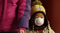 Seorang anak memakai masker saat mengunjungi taman Jingshan pada hari bersalju di Beijing, China, Selasa (19/1/2021). China sekarang berurusan dengan pandemi virus corona di timur lautnya yang dingin, mendorong penguncian ketat dan pembatasan perjalanan. (AP Photo/Ng Han Guan)
