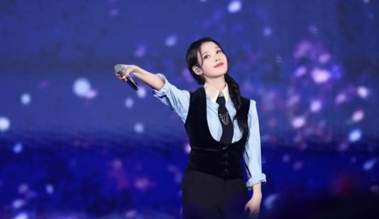Tak melulu dress dan feminim, di atas panggung, IU tampil kasual mengenakan kemeja biru lengan panjang dipadukan vest dan celana hitam lengkap dengan dasinya. [@dlwlrma]