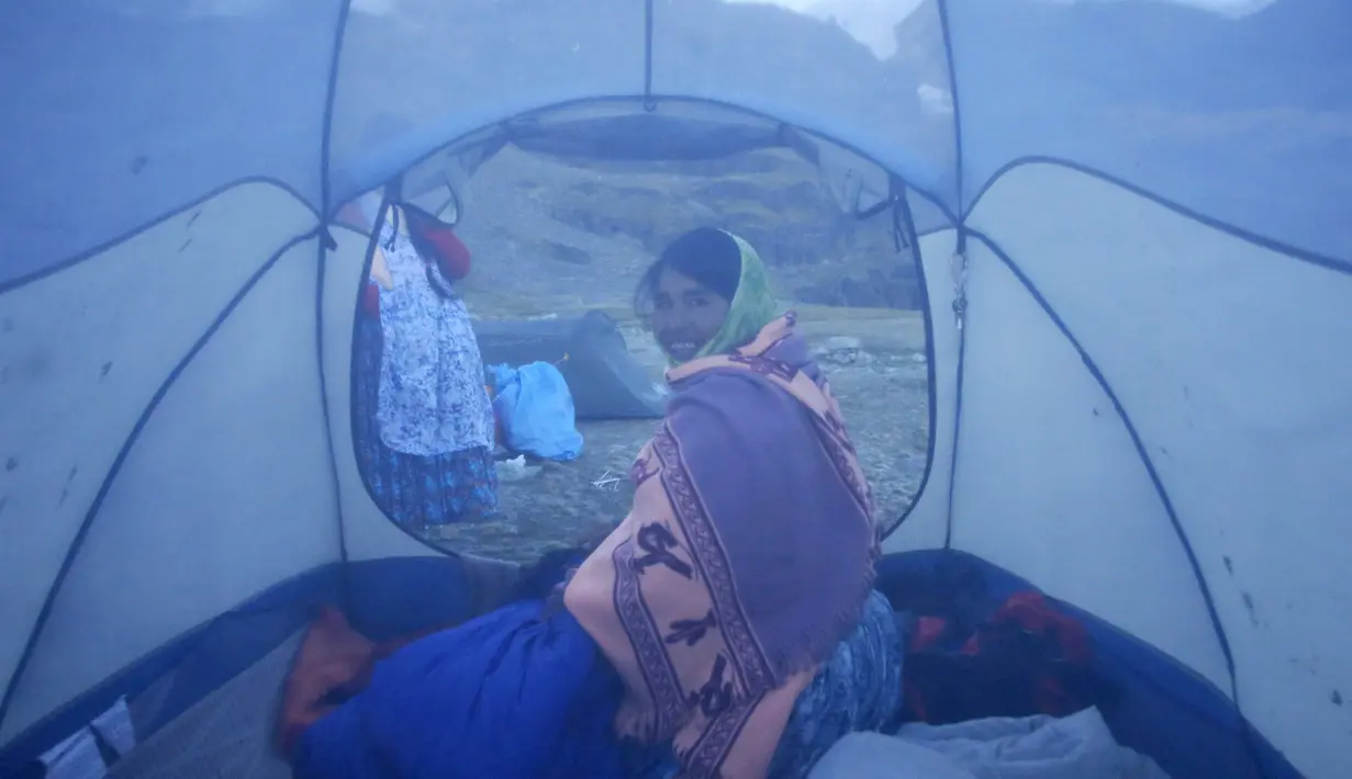 Perempuan suku Aymara duduk di tendanya sebelum naik gunung Illimani, di Paz, Bolivia, (16/4). Perempuan suku Aymara yang berprofesi sebagai tukang masak dan angkut barang atau porter ini selalu mengenakan pakaian tradisional. (REUTERS/David Mercado)