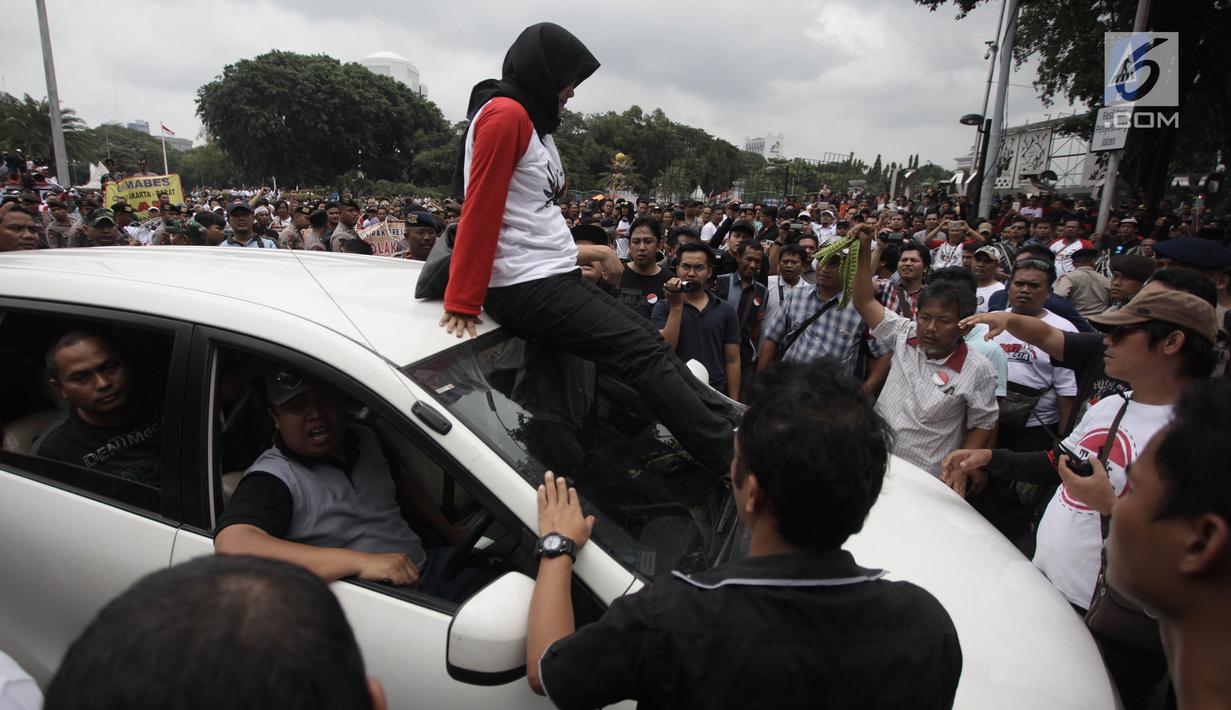 Demonstran berusaha mencegat driver online yang masih beroperasi saat unjuk rasa di depan Istana Negara, Jakarta, Rabu (14/2). Aksi pemberhentian mobil taksi online itu membuat situasi tegang antar pengemudi dan demonstran. (Liputan6.com/Arya Manggala)