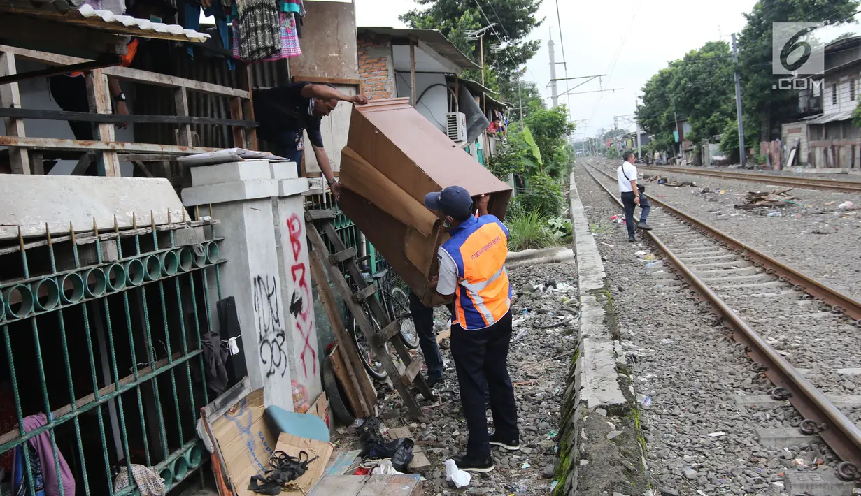 Petugas memindahkan lemari milik warga setempat saat melakukan penertiban lapak dan bangunan liar di sepanjang jalur kereta di kawasan Grogol, Jakarta Barat, Kamis (22/2). (Liputan6.com/Arya Manggala)