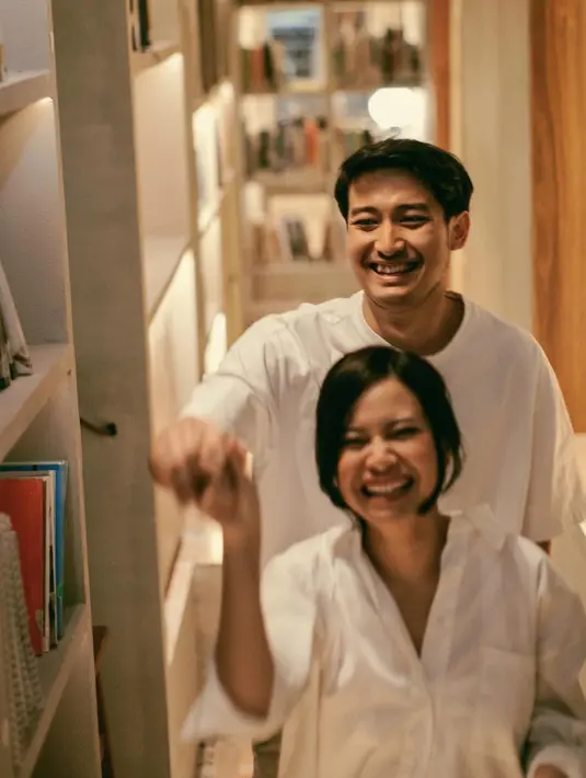 Dipotret di antara rak buku di rumah, Hanggini dan Luthfi terlihat serasi dengan busana serba putih [@byjatidiriono]