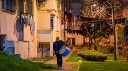 Tradisi ini dimulai di distrik Fatih dekat semenanjung bersejarah Istanbul, tempat sebagian besar penabuh gendang Ramadan saat ini berasal dari komunitas Roma Turki. Tampak dalam foto, seorang pemain drum Turki memainkan drum dan menyanyikan lagu-lagu tradisional di jalanan Istanbul, untuk membangunkan umat Muslim untuk sahur, yaitu makan malam Ramadan, pada 24 Februari 2026. (Yasin AKGUL/AFP)