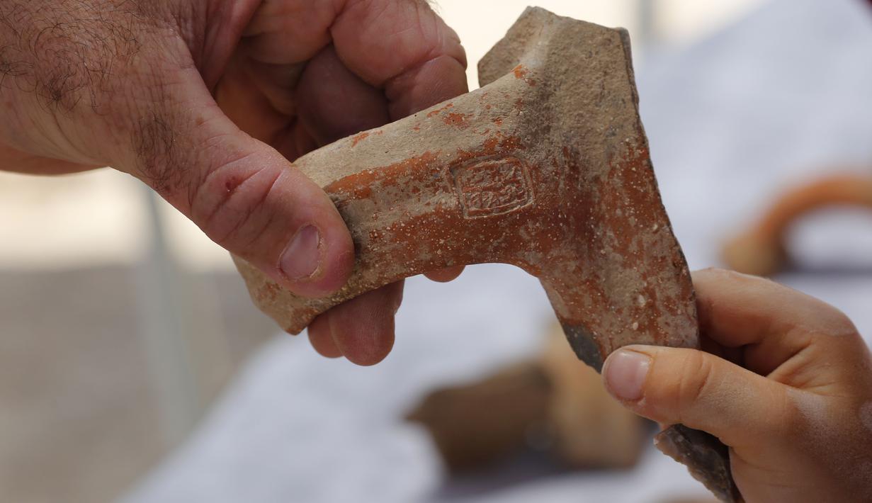 Seorang arkeolog menunjukkan sebuah stempel bertuliskan huruf Ibrani kuno yang ditemukan di sebuah situs penggalian di Yerusalem (22/7/2020). Tim arkeolog Israel menemukan pusat penyimpanan administratif berusia 2.700 tahun di Yerusalem. (Xinhua/Gil Cohen Magen)