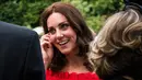 Kate Middleton berbincang dengan para tamu saat menghadiri acara 'Queen's Birthday Garten Party' di kediaman duta besar Inggris di Berlin, Rabu (19/7). Dalam acara itu, Kate Middleton tampil  anggun dalam balutan gaun merah (Matthias Nareyek/Pool via AP)