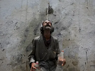 Seorang pria mendinginkan kepalanya di kucuran air keran usai mengisi botol saat cuaca panas yang ekstrem di Karachi, Pakistan, (23/6/2015). Gelombang panas yang telah menewaskan lebih dari 400 jiwa di kota selatan Pakistan. (REUTERS/Akhtar Soomro)