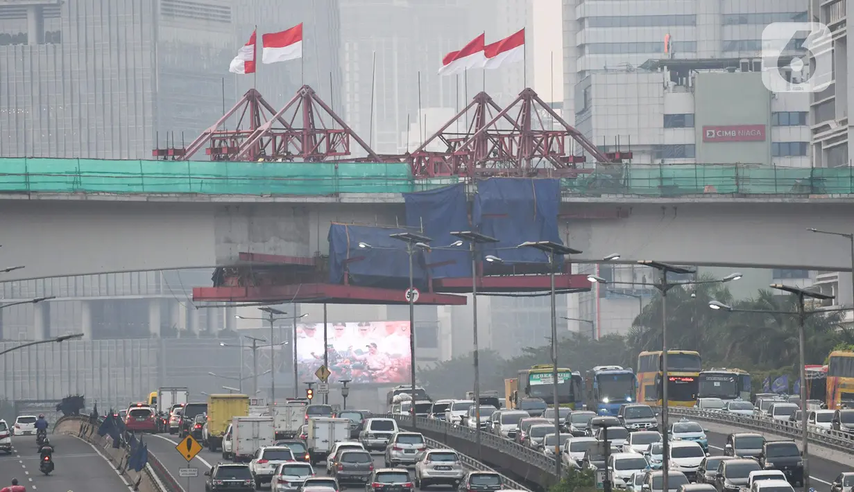 Kendaraan melintas berlatar pembangunan bentangan beton lintasan LRT di Jalan Gatot Subroto Jakarta, Kamis (7/11/2019). Saat ini pembangunan tiang pancang yang membentang di atas ruas jalan tol tersebut sudah tersambung. (Liputan6.com/Immanuel Antonius)
