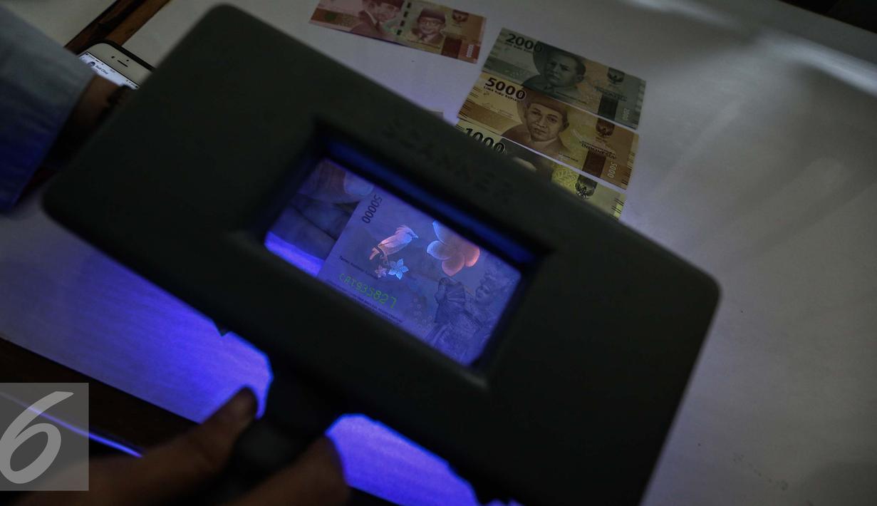 Petugas menunjukan alat untuk melihat gambar yang tersembunyi di uang kertas rupiah di kantor Peruri, Karawang, Jawa Barat, Rabu (18/1). (Liputan6.com/Faizal Fanani)