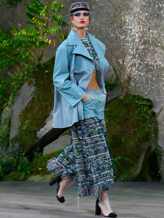 Model berpose di catwalk saat memamerkan koleksi Spring/Summer 2018 untuk Chanel selama Paris Fashion Week, Selasa (3/10). Gaya para model tersebut dilengkapi dengan sepatu, topi, sarung tangan dan ponco plastik. (AP Photo/Francois Mori)