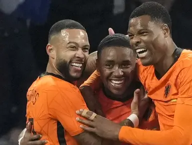 Pemain Belanda Memphis Depay (kiri) dan Denzel Dumfries (kanan) memeluk Steven Bergwijn (tengah) yang mencetak gol ke gawang Denmark pada pertandingan persahabatan di Johan Cruyff ArenA, Amsterdam, Belanda, 26 Maret 2022. Belanda menang 4-2. (AP Photo/Peter Dejong)