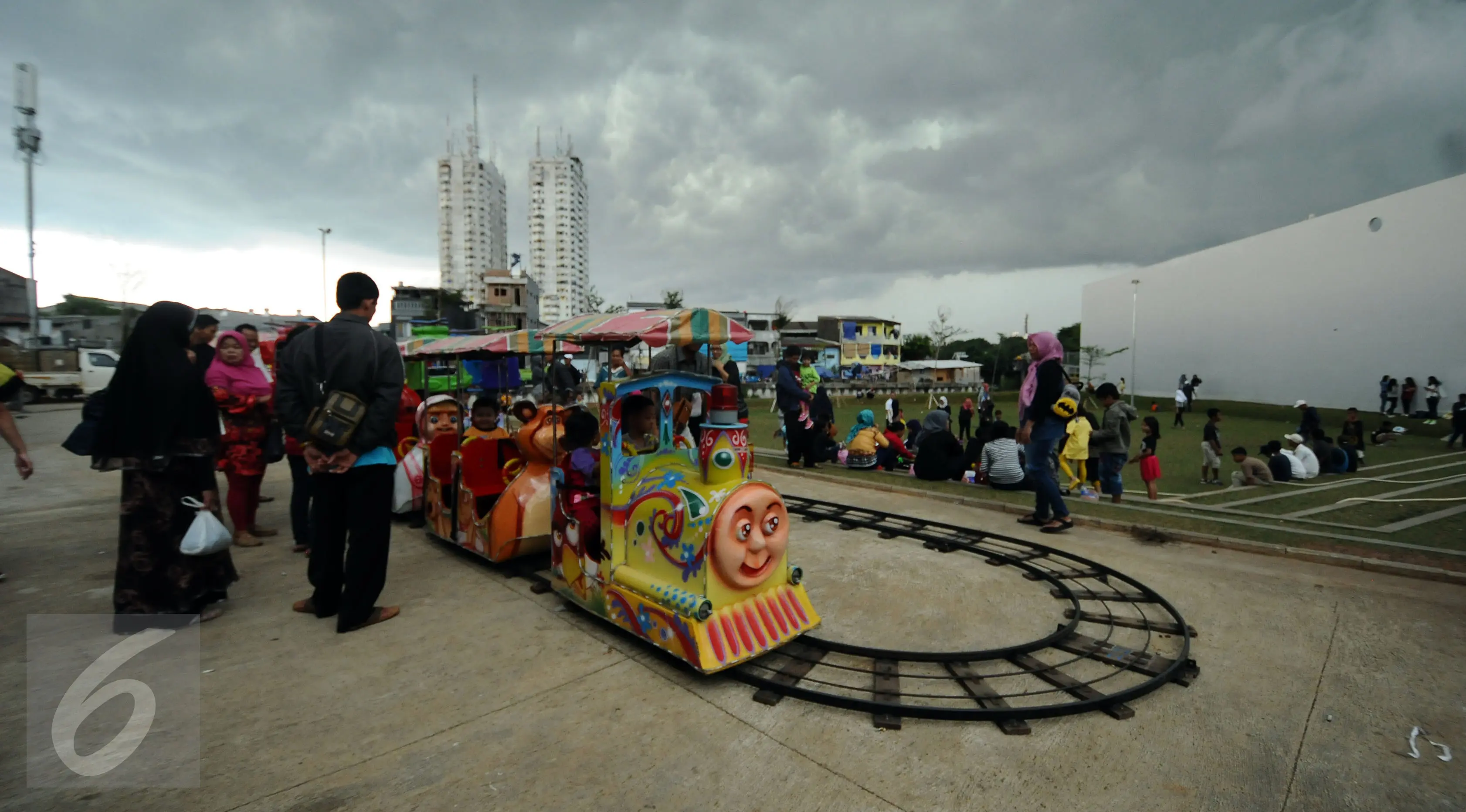 Sejumlah warga antre di dekat permainan kereta yang ada di areal RPTRA Kalijodo, Jakarta, Selasa (28/3). Sejumlah warga menghabiskan libur Hari Raya Nyepi dengan mengajak putera puterinya bermain di areal RPTRA Kalijodo. (Liputan6.com/Helmi Fithriansyah)