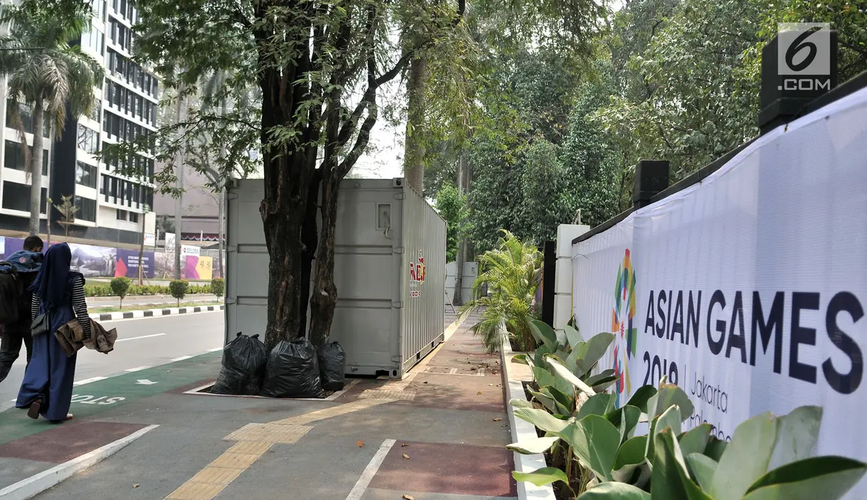 Pengendara sepeda melintas dekat kontainer tiket Asian Games 2018 yang berdiri di sepanjang trotoar Jalan Pintu 1 Senayan, Jakarta, Selasa (7/8). (Merdeka.com/Iqbal Nugroho)