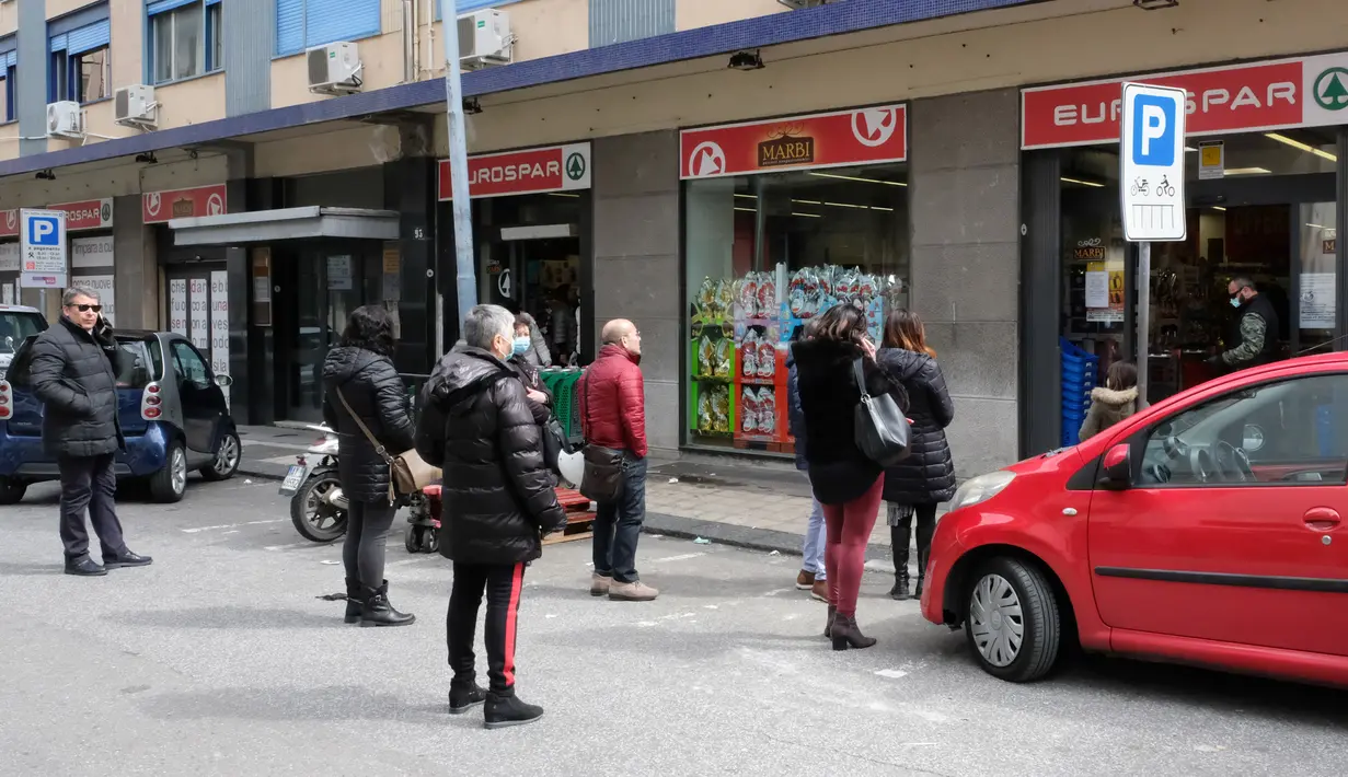 Orang-orang menjaga jarak saat antre memasuki supermarket di Messina, Sisilia pada 10 Maret 2020. Wabah Virus Corona memaksa Italia memberlakukan Lock Down yang mencakup tidak adanya pertemuan di ruang publik, hingga anjuran agar menjaga jarak, bahkan ketika beribadah. (Giovanni ISOLINO/AFP)