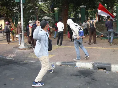 Pelajar melempari Gedung DPR dengan batu saat berunjuk rasa di Palmerah, Jakarta, Rabu (25/9/2019). Pihak kepolisian menembakan gas air mata untuk memukul mundur pelajar. (Liputan6.com/Angga Yuniar)