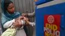 Seorang petugas kesehatan memberikan tetes vaksin polio kepada seorang anak saat kampanye vaksinasi polio dari rumah ke rumah di sebuah kawasan kumuh di Lahore, Paksistan, Senin (23/5/2022). Pakistan meluncurkan upaya anti-polio baru pada hari Senin, lebih dari seminggu setelah pejabat mendeteksi kasus ketiga tahun ini di wilayah barat laut negara itu yang berbatasan dengan Afghanistan. (Arif ALI / AFP)