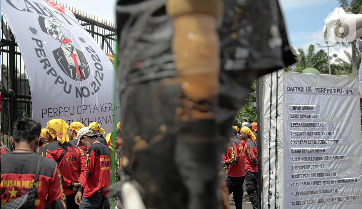 Puluhan elemen buruh menggeruduk gedung DPR RI, Jakarta, Selasa (10/1/2023). Massa juga menggantung banner besar bertuliskan "cabut Perppu No 2 Tahun 2022" di pintu utama Gedung DPR. (Liputan6.com/Faizal Fanani)