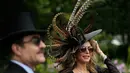 Racegoers dengan hiasan kepala tiba pada hari pertama ajang pacuan kuda Royal Ascot di Inggris, Selasa (19/6). Di acara ini para bangsawan wanita memakai topi dengan desain unik untuk meramaikan acara yang telah diadakan sejak 1711. (AP/Tim Ireland)