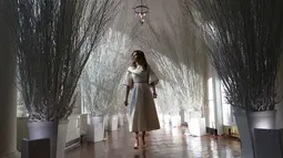 Ibu Negara Amerika Serikat (AS), Melania Trump berjalan di sepanjang lorong East Colonnade yang didekorasi untuk perayaan Natal dengan tema "Time-Honored Traditions" di Gedung Putih, Washington DC, Senin (27/11). (AP Photo/Carolyn Kaster)