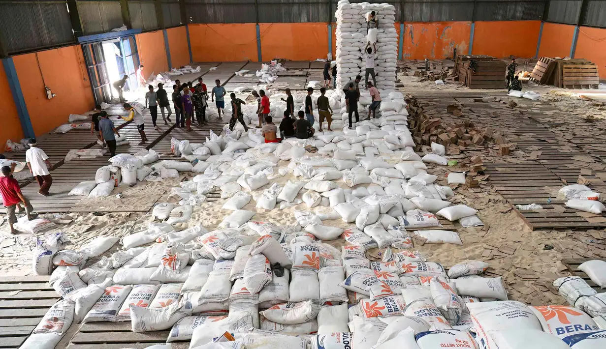 Sebelumnya, pada akhir bulan lalu, terjadi penjarahan gudang Bulog yang berada di Kecamatan Sarudik, Kota Sibolga. Tampak dalam foto, warga desa menerima bahan pangan pokok yang didistribusikan di tengah upaya bantuan dari gudang beras pemerintah di Sarudik, Tapanuli Tengah, Provinsi Sumatra Utara, pada Rabu 3 Desember 2025. (YT Hariono/AFP)