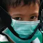 Seorang anak laki-laki mengenakan masker saat dijemput orang tuanya di Bangkok (30/1). Kementerian Kesehatan Thailand memberi peringatan kepada warga dan turis untuk menghindari kegiatan di ruang terbuka dan mengenakan masker. (AP Photo/Sakchai Lalit)